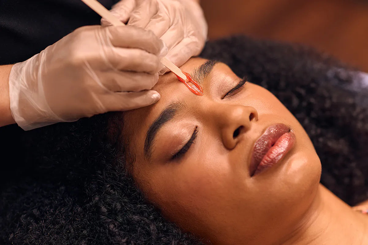 Person receiving a facial treatment with gloved hands applying a product to the face.